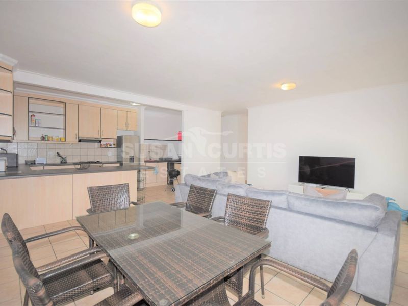 Open-plan living area featuring a kitchen with built-in cabinetry, breakfast counter, and tiled flooring throughout the combined dining and lounge space.