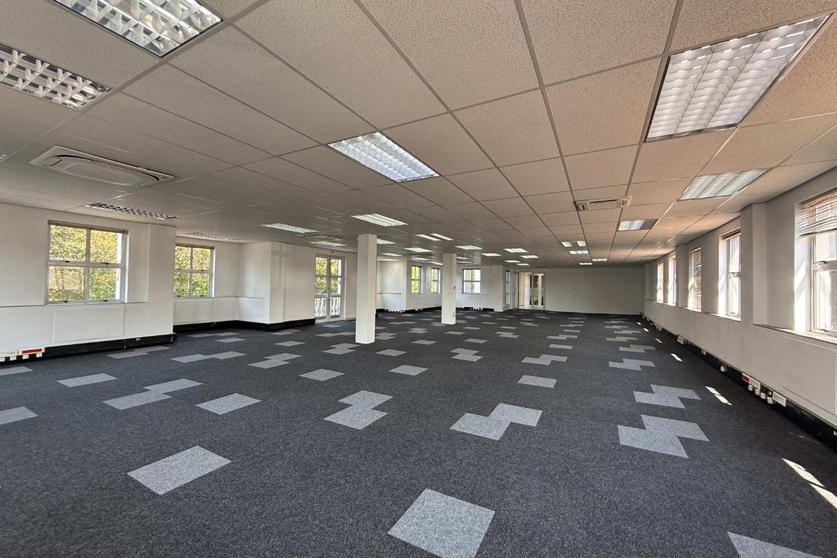 Spacious open-plan office area featuring suspended ceilings, recessed lighting, carpet tiles, and perimeter trunking, offering a clean and functional workspace.