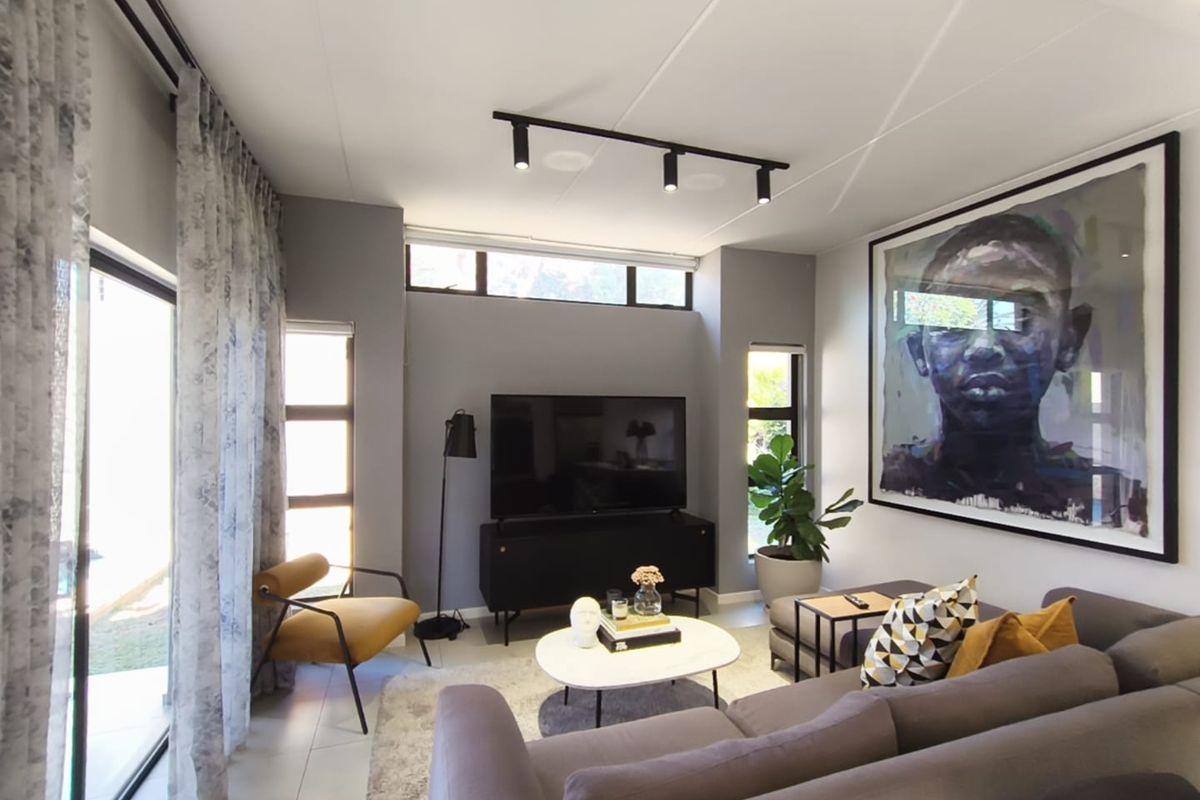 Modern living room featuring tiled flooring, track lighting, and large sliding glass doors that provide ample natural light and access to the outdoors.