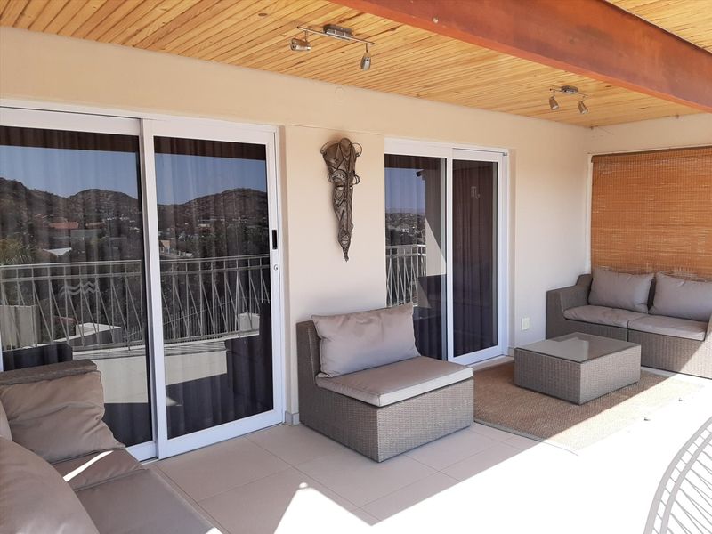 A covered balcony featuring a timber ceiling, tiled flooring, and large sliding glass doors providing access to the interior living space.