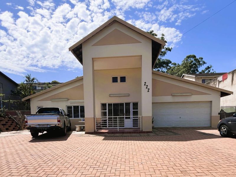 Front elevation of a residential house featuring a paved driveway, double garage, and a prominent central entrance structure.