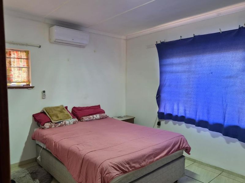 A functional bedroom featuring tiled flooring and a wall-mounted split-system air conditioner.