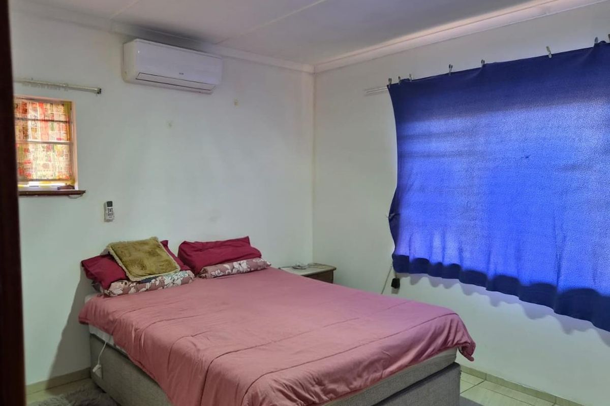 A functional bedroom featuring tiled flooring and a wall-mounted split-system air conditioner.