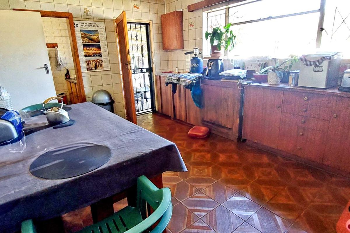 A dated kitchen featuring wooden cabinetry, tiled walls, and floor tiles, offering a functional layout with direct access to an exterior door.