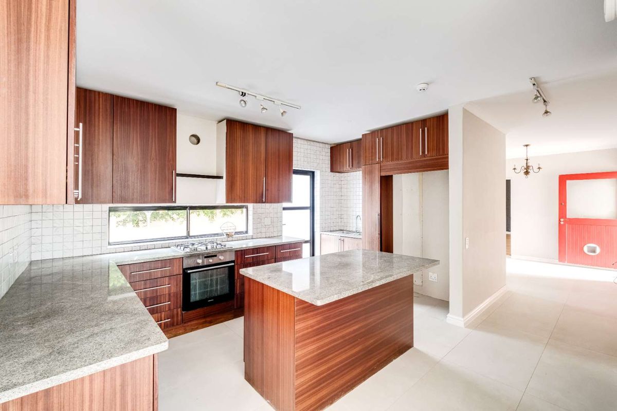 Modern kitchen featuring wood-grain cabinetry, granite countertops, a central island, and integrated stainless steel oven and gas hob.
