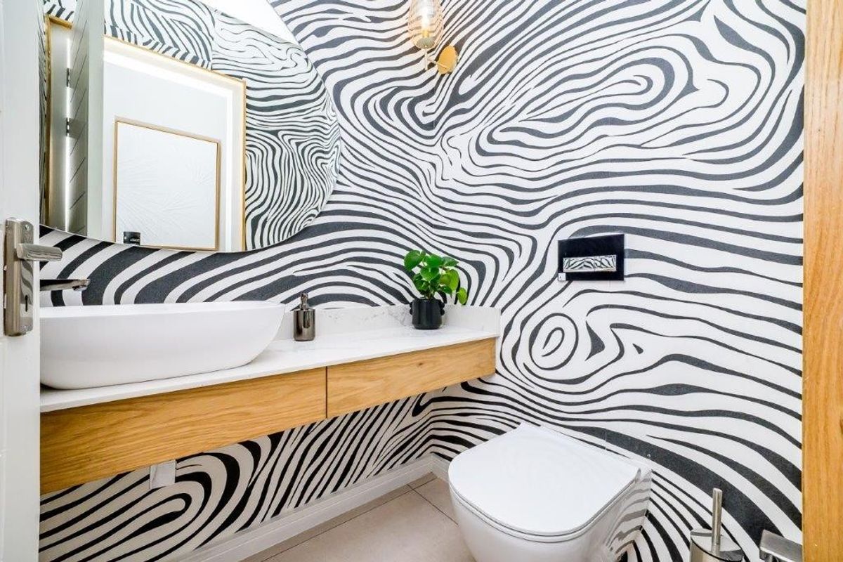Modern powder room featuring a floating timber vanity, stone countertop, vessel sink, and a wall-mounted toilet with a bold patterned feature wall.