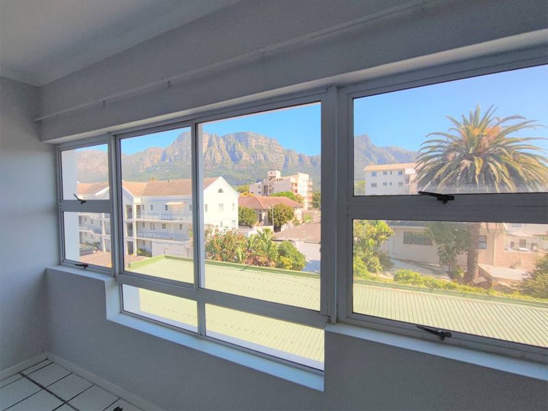 An interior view from a window showcasing a scenic mountain landscape and surrounding residential neighbourhood.