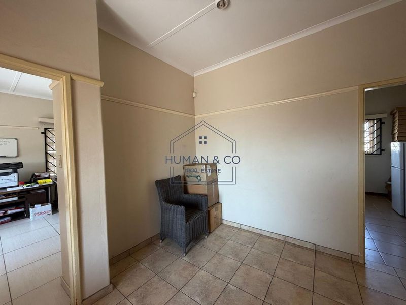 A functional hallway space featuring neutral wall tones, tiled flooring, and classic picture rail detailing, connecting multiple rooms within the property.