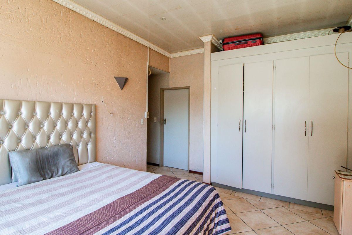 Bedroom featuring built-in cupboards, tiled flooring, and textured wall finishes.