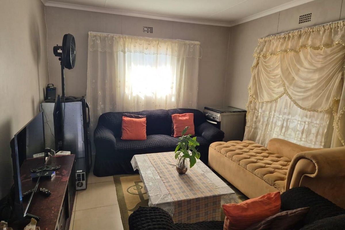 A living room featuring tiled flooring and dual windows with curtains, providing a functional space for relaxation.