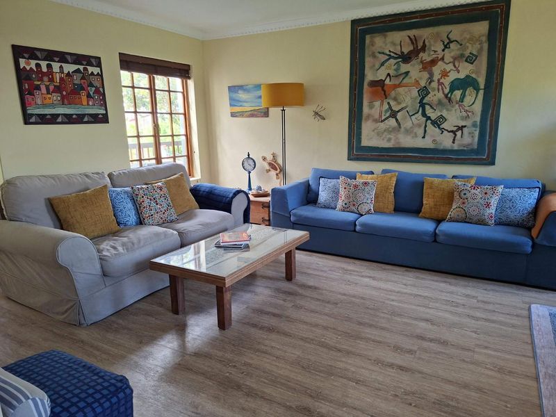 A comfortable living room featuring light-toned laminate flooring, crown molding, and a timber-framed window, providing a bright and inviting space.