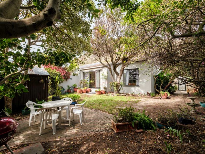 A private rear garden featuring a brick-paved patio area, mature trees, and direct access to the home through sliding glass doors.