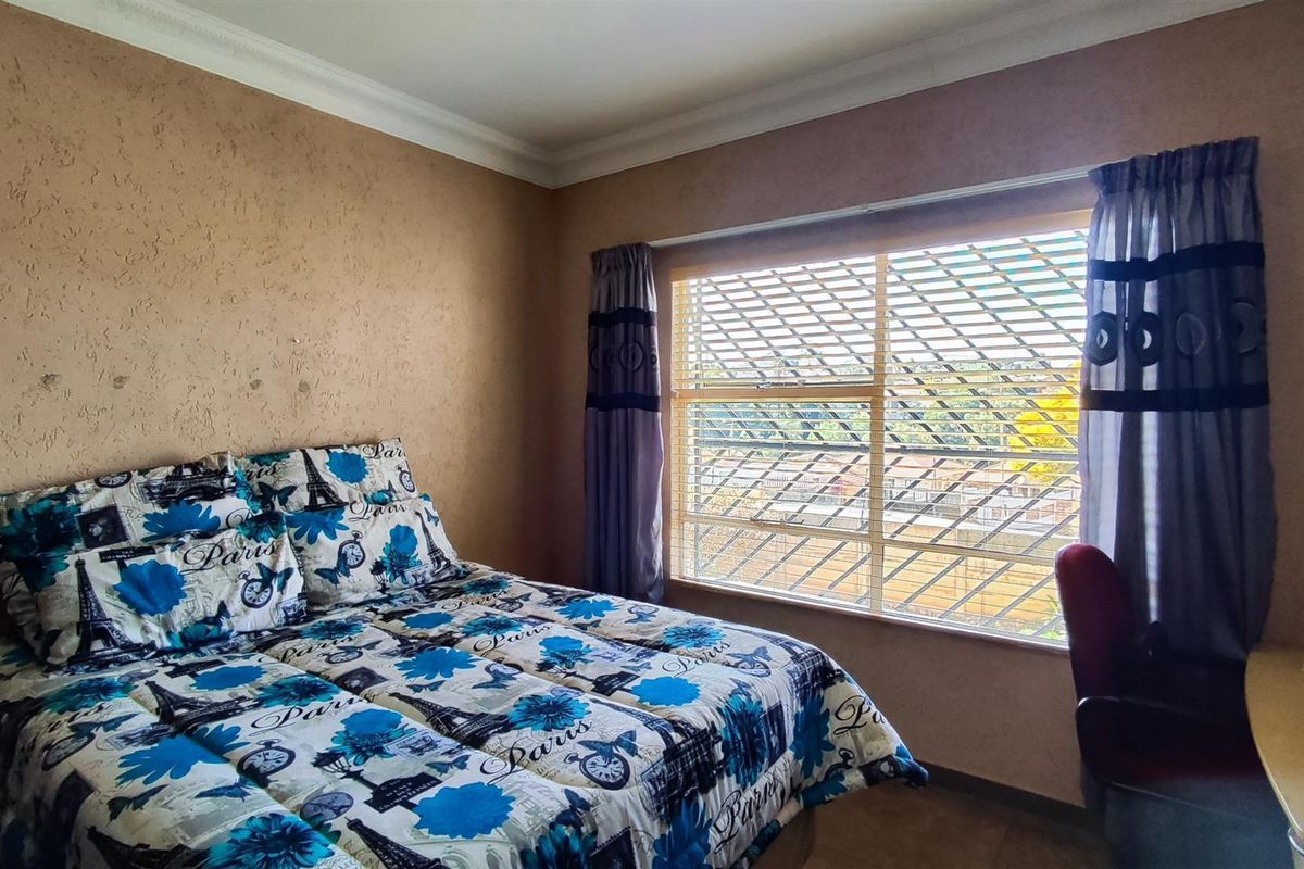 A bedroom featuring textured walls, crown molding, and a window fitted with security bars, offering a functional space with potential for cosmetic updates.