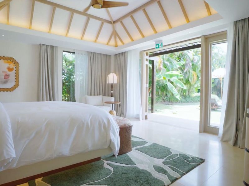 Spacious bedroom featuring a vaulted ceiling with integrated lighting, ceiling fan, and large sliding glass doors opening to a private garden area.