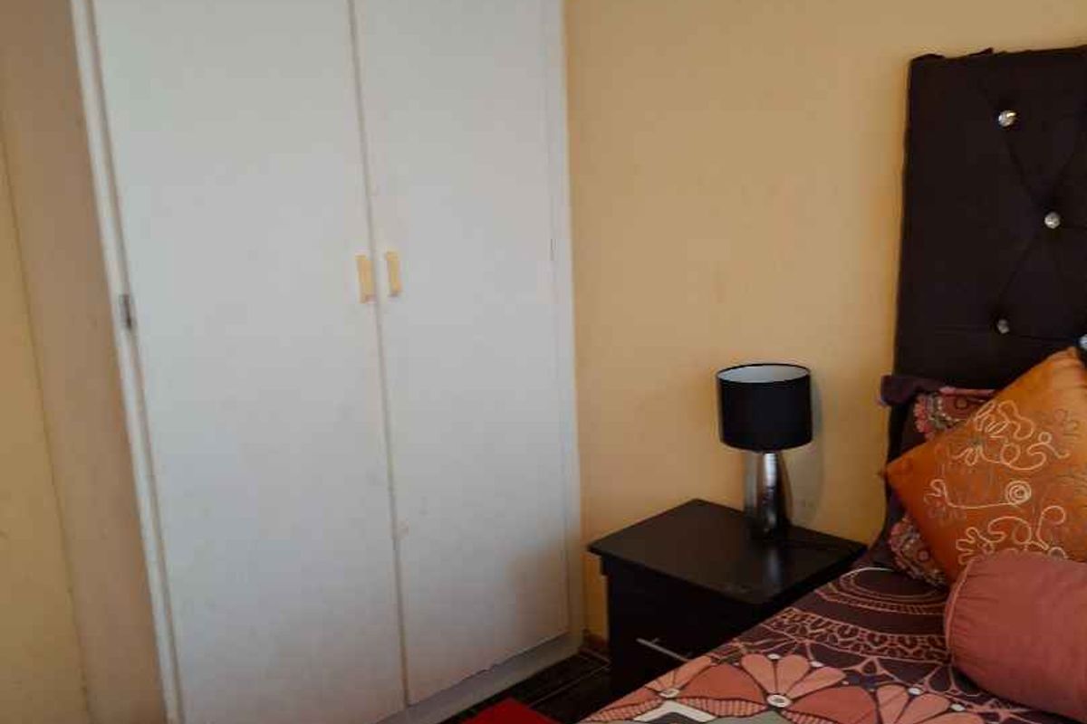 A bedroom featuring a built-in wardrobe with white doors and decorative ceiling cornicing.