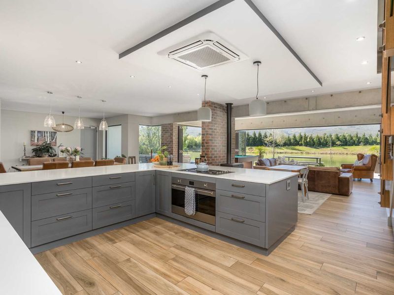 Spacious open-plan kitchen and living area featuring a modern island, high-end built-in appliances, exposed brick and concrete elements, and seamless flow to the outdoor patio.