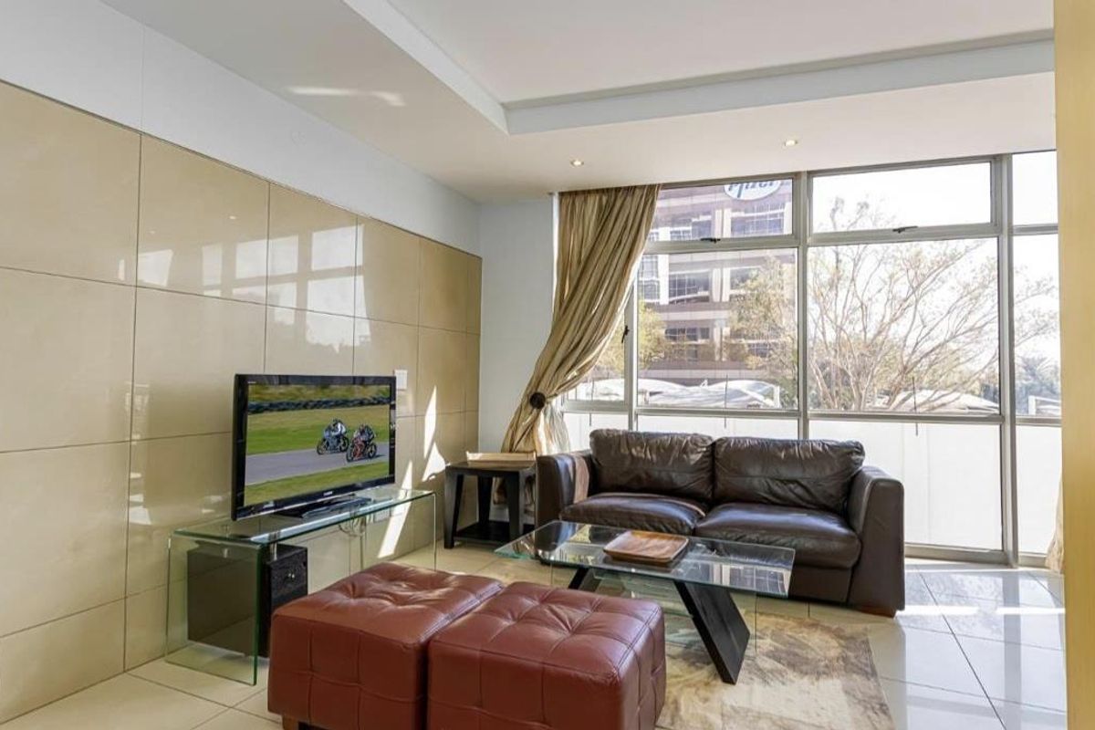 A bright living room featuring large floor-to-ceiling windows, tiled flooring, and a feature wall with glossy paneling.