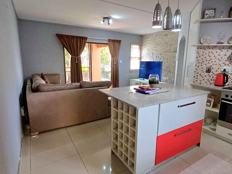 Open-plan living area featuring a kitchen island, built-in oven, stone feature wall, and direct access to a patio through sliding glass doors.