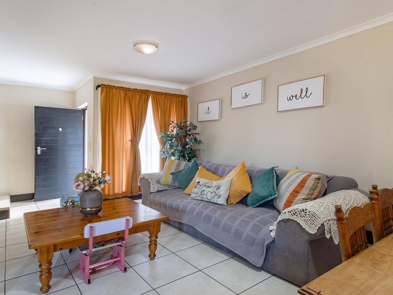 A bright living room featuring tiled flooring, a staircase, and neutral wall finishes, providing a functional and open living space.