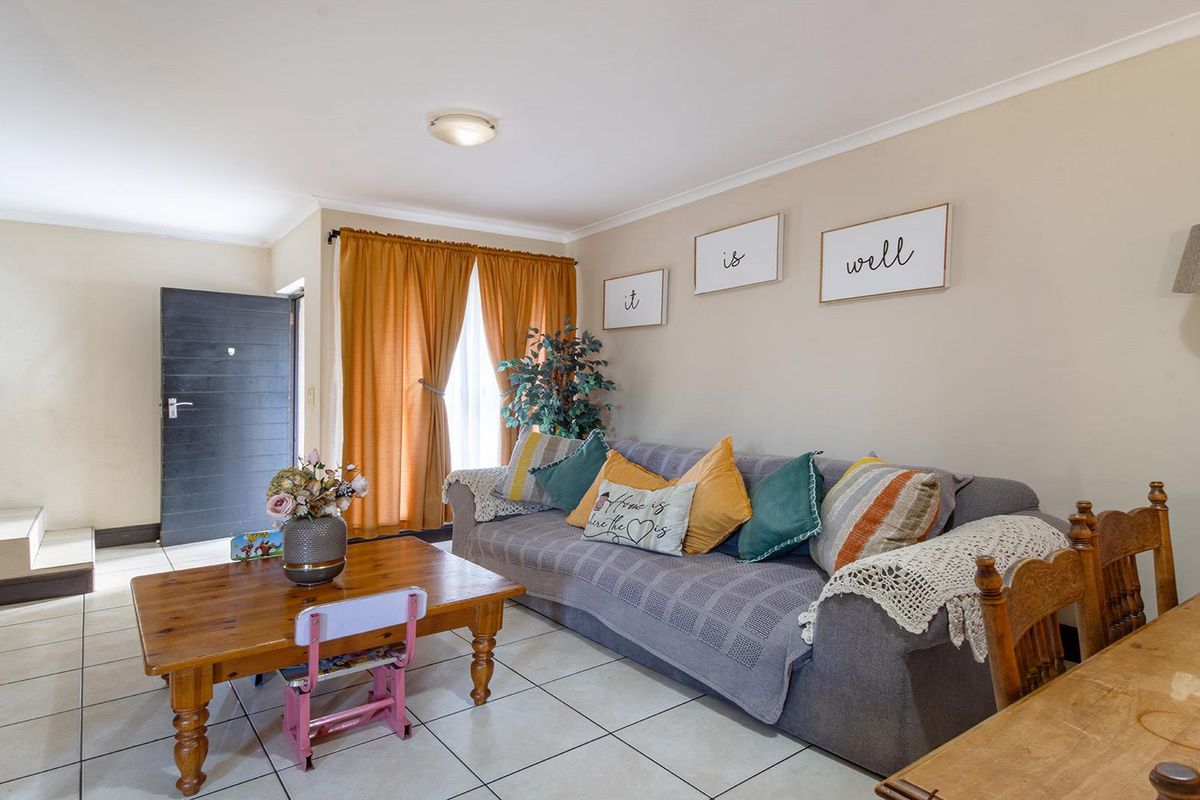 A bright living room featuring tiled flooring, a staircase, and neutral wall finishes, providing a functional and open living space.