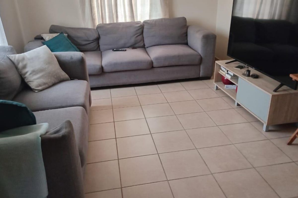 A comfortable living room featuring neutral ceramic floor tiles and natural light from the window.