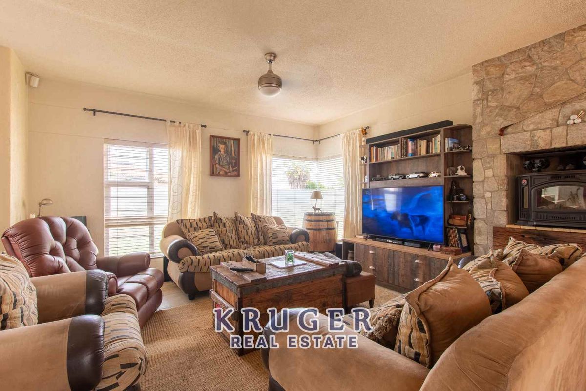 A comfortable living room featuring a prominent stone-clad fireplace with a built-in wood-burning stove and large windows allowing for natural light.