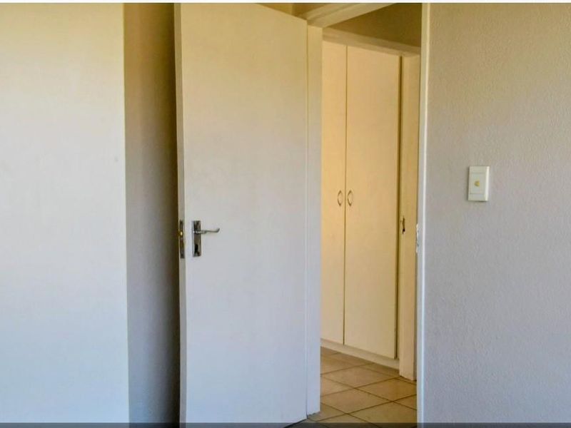 A clean, empty hallway featuring built-in cupboards and tiled flooring, providing a neutral transition space between rooms.