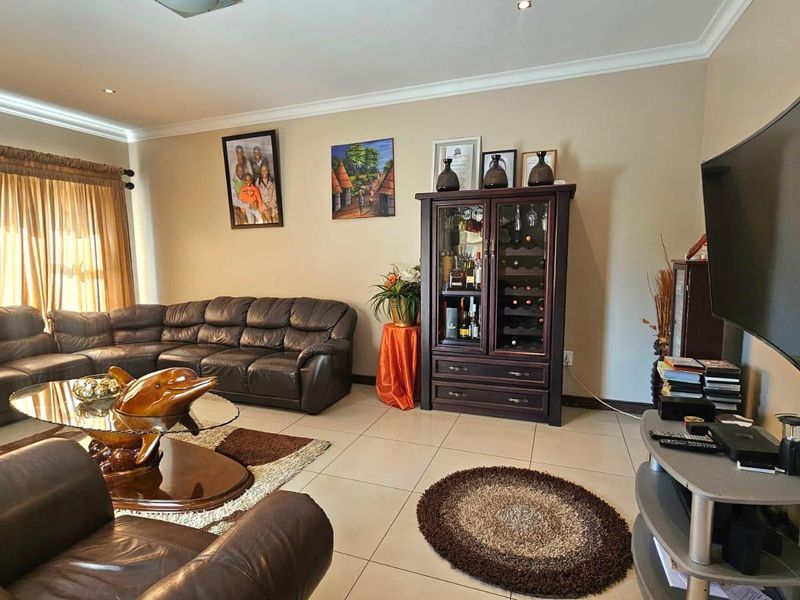 A spacious living room featuring neutral wall tones, tiled flooring, and recessed ceiling lighting, providing a comfortable and well-maintained family area.