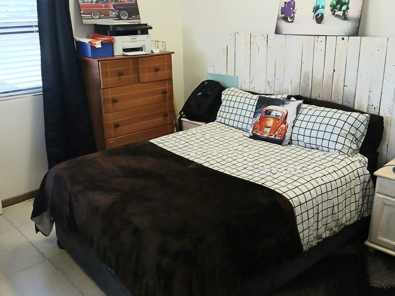 A functional bedroom featuring tiled flooring and window blinds, providing a neutral base for potential interior updates.