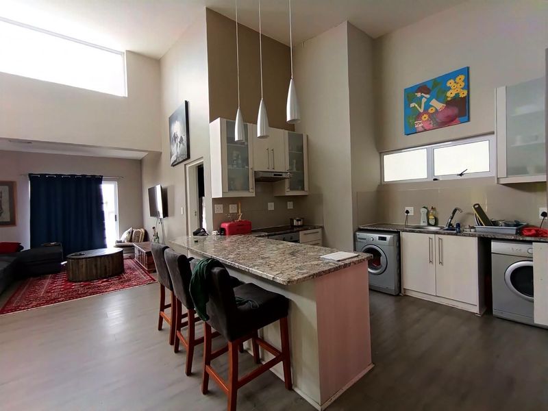 Open-plan living and kitchen area featuring high ceilings, granite countertops, built-in cabinetry, and integrated laundry appliances.