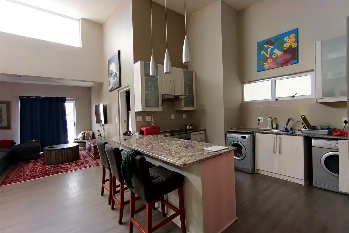 Open-plan living and kitchen area featuring high ceilings, granite countertops, built-in cabinetry, and integrated laundry appliances.