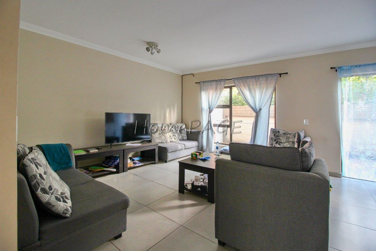 Spacious living room featuring large format floor tiles, neutral wall tones, and sliding glass doors providing direct access to the outdoor area.