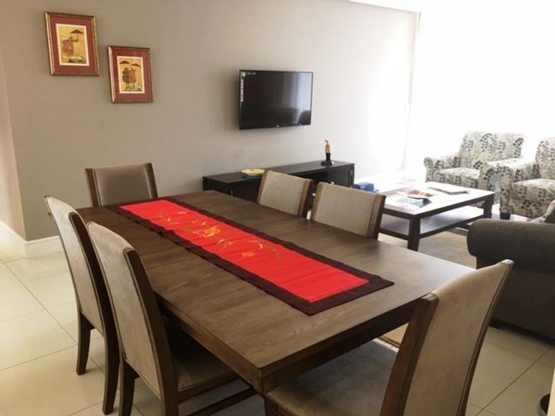 An open-plan living and dining area featuring neutral wall tones and light-colored tiled flooring, providing a functional space for relaxation and dining.