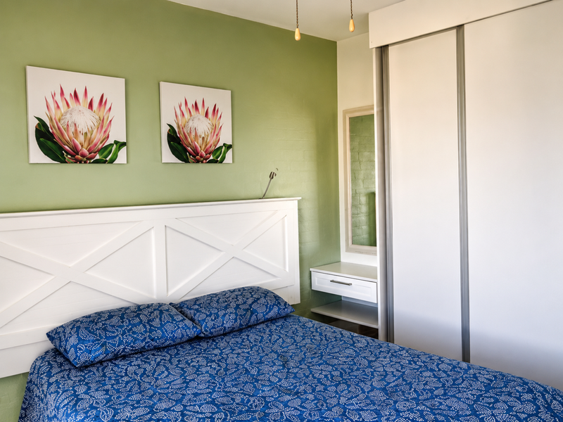 A well-maintained bedroom featuring a built-in wardrobe, integrated vanity unit, and a feature wall with neutral finishes.