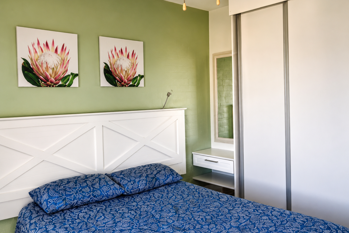 A well-maintained bedroom featuring a built-in wardrobe, integrated vanity unit, and a feature wall with neutral finishes.