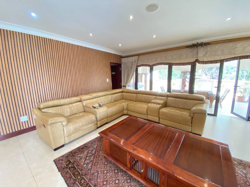 Spacious living room featuring modern slatted timber wall paneling, tiled flooring, and large sliding glass doors providing access to the outdoor area.