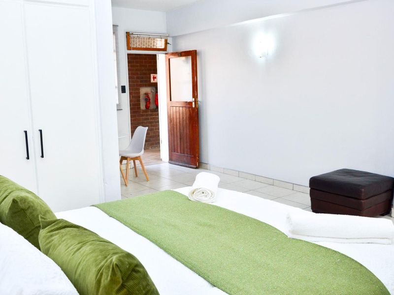A bedroom featuring tiled flooring, a built-in wardrobe, and a timber door leading to an adjacent space.