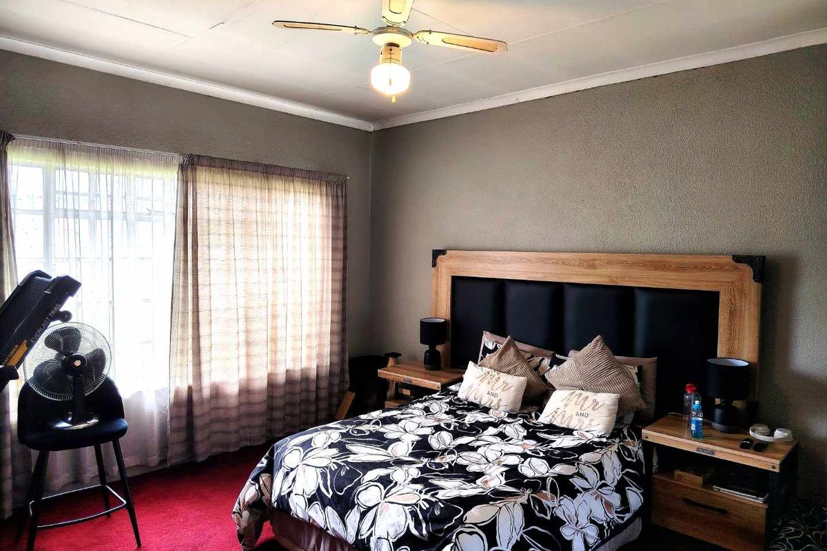 A bedroom featuring a ceiling fan and large window with natural light, providing a functional space for rest.