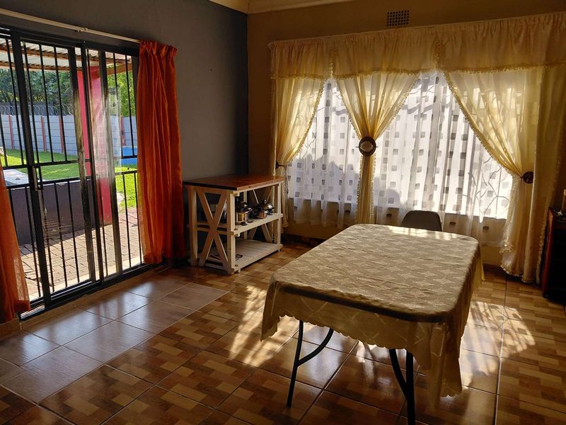 A living area featuring tiled flooring, a large window with curtains, and a sliding glass door providing access to the outdoor space.