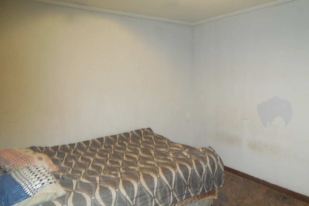 A bedroom space featuring plain walls and worn flooring, requiring cosmetic updates and refurbishment to improve its overall condition and appeal.