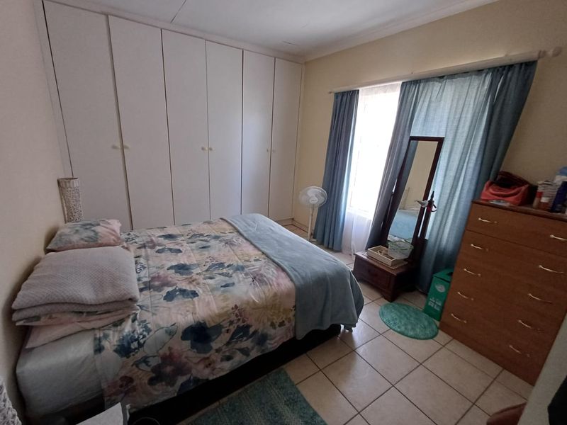 A functional bedroom featuring built-in cupboards and tiled flooring, offering a practical layout with natural light from the window.