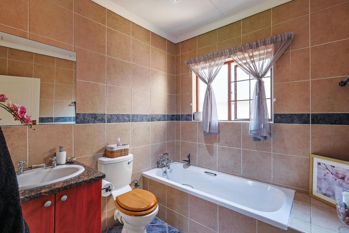 A functional bathroom featuring a built-in bathtub, vanity with basin, and tiled walls throughout.