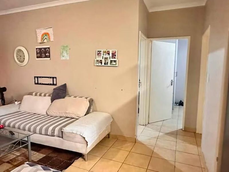 A living room area featuring neutral wall tones, tiled flooring, and coved ceilings, providing access to adjacent rooms through internal doorways.