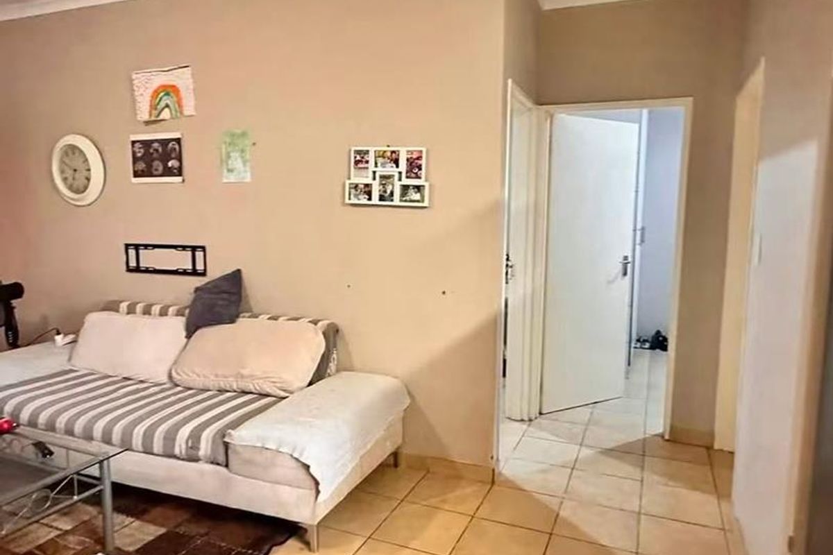 A living room area featuring neutral wall tones, tiled flooring, and coved ceilings, providing access to adjacent rooms through internal doorways.