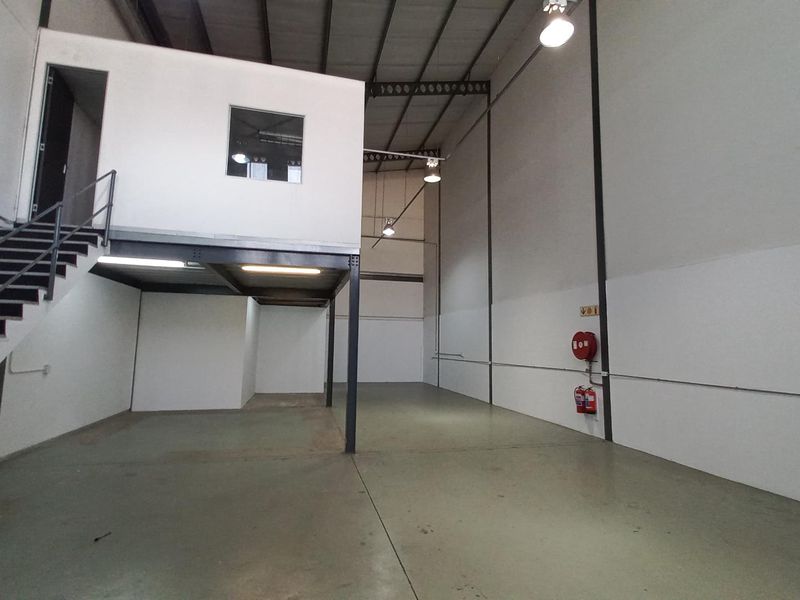 Spacious industrial warehouse unit featuring a mezzanine level, high ceilings, concrete flooring, and integrated fire safety equipment.