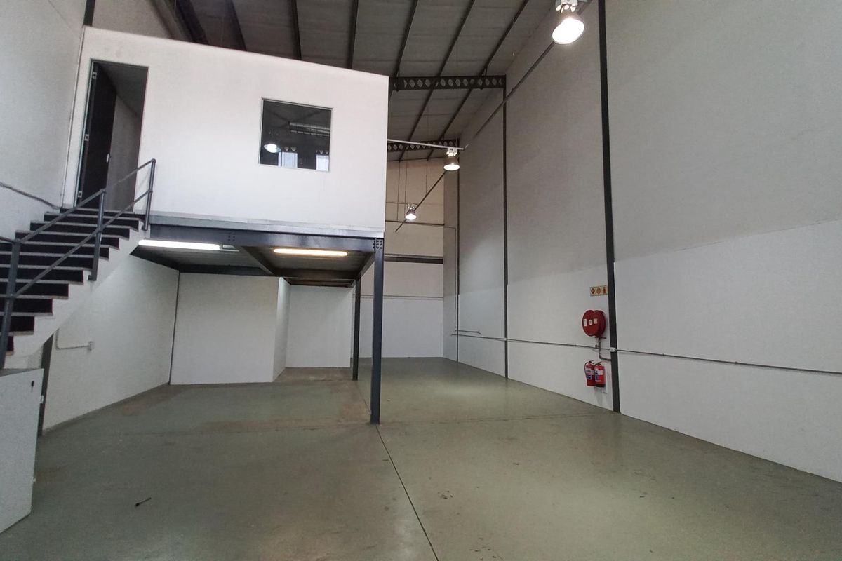 Spacious industrial warehouse unit featuring a mezzanine level, high ceilings, concrete flooring, and integrated fire safety equipment.