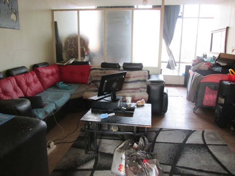A living room area featuring large windows for natural light and a frosted glass partition, providing a functional layout with tiled flooring.