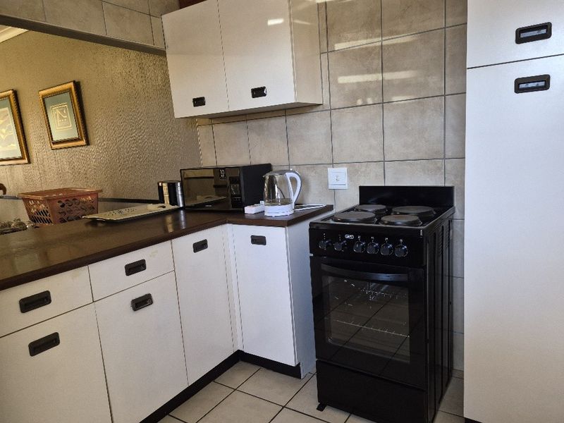 A functional kitchen featuring white cabinetry, tiled backsplash, and a black freestanding electric stove with oven.
