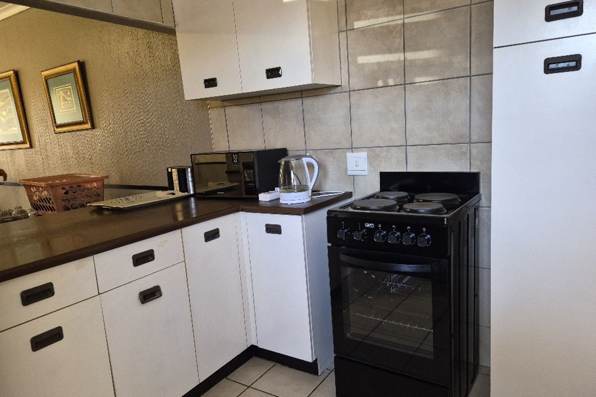 A functional kitchen featuring white cabinetry, tiled backsplash, and a black freestanding electric stove with oven.