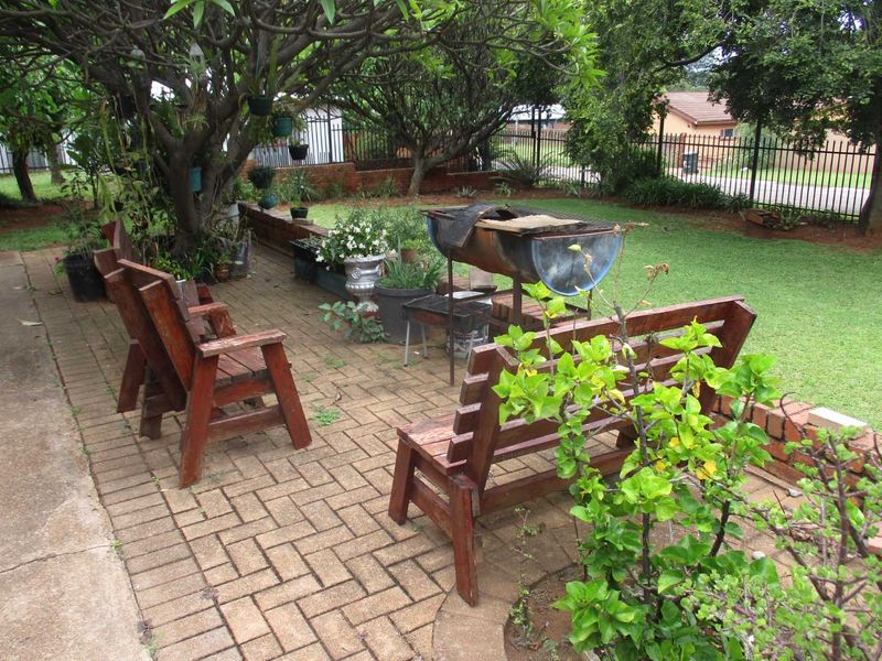 A paved outdoor patio area featuring a retaining wall and established garden surroundings, providing a functional space for outdoor relaxation.